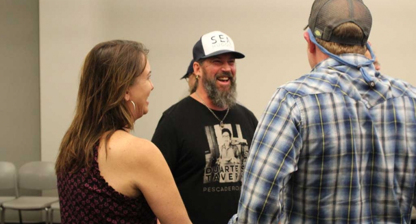 A group of adults smile at a family seminar after an outward bound course